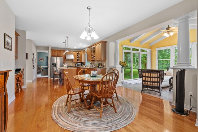 6380 Mcgillicuddy Ln, Portage, MI 49024 - dining room with ornate columns, light wood finished floors, vaulted ceiling, ceiling fan, and a chandelier