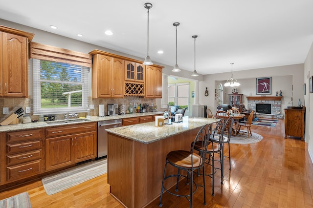 6380 Mcgillicuddy Ln, Portage, MI 49024 - kitchen featuring stainless steel dishwasher, a center island, a fireplace with raised hearth, a kitchen breakfast bar, and light wood-style floors