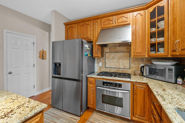 6380 Mcgillicuddy Ln, Portage, MI 49024 - kitchen featuring stainless steel appliances, extractor fan, glass insert cabinets, light stone countertops, and backsplash