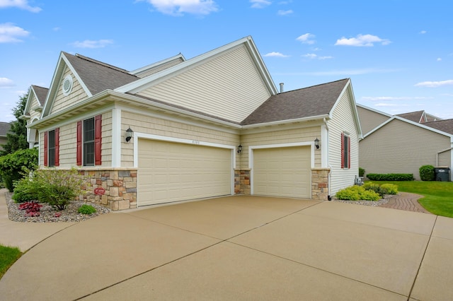 6380 Mcgillicuddy Ln, Portage, MI 49024 - view of side of home featuring stone siding, an attached garage, driveway, and roof with shingles