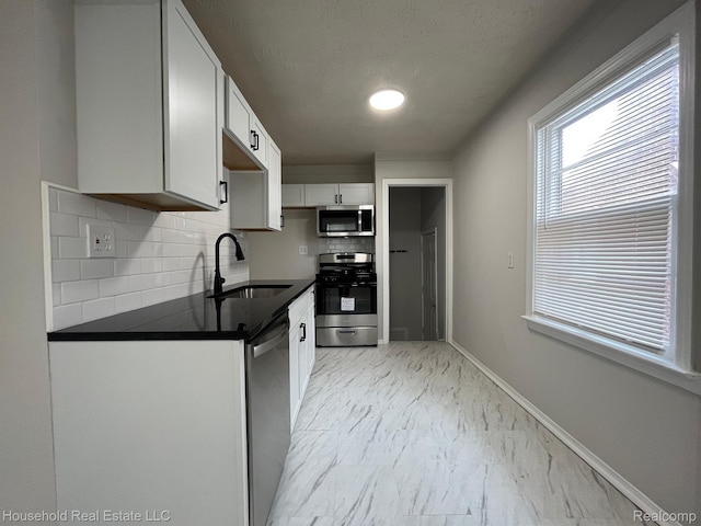 14722 Lydia Ave, Eastpointe, MI 48021 - kitchen with stainless steel appliances, light marble finish floors, backsplash, dark countertops, and white cabinetry