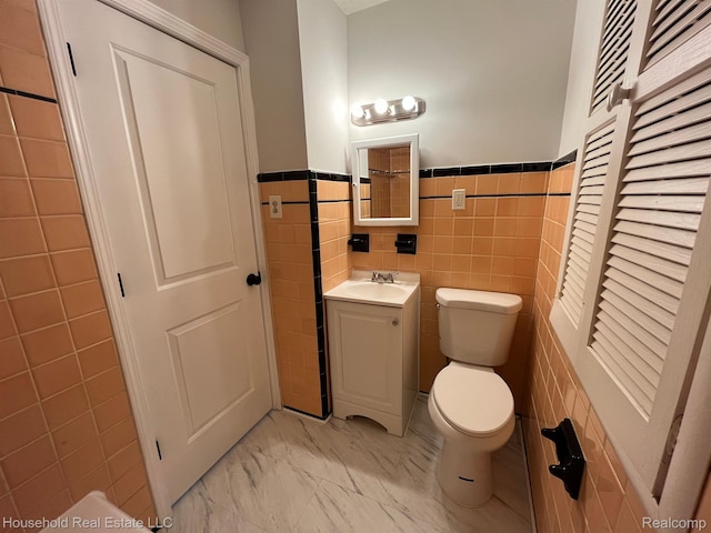 14722 Lydia Ave, Eastpointe, MI 48021 - bathroom featuring vanity, tile walls, marble finish flooring, and wainscoting