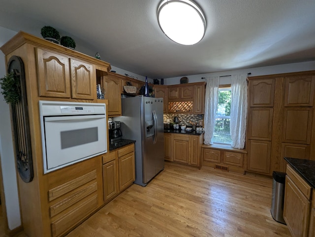 2740 Booth Rd, Au Gres, MI 48703 - kitchen with oven, stainless steel fridge, light wood finished floors, tasteful backsplash, and brown cabinets