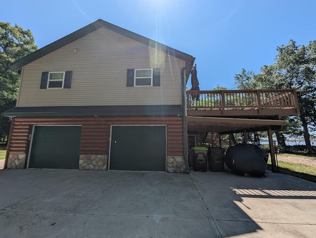 2740 Booth Rd, Au Gres, MI 48703 - view of side of property featuring driveway, an attached garage, stone siding, and a wooden deck