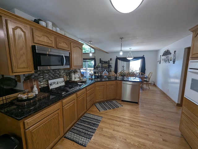 2740 Booth Rd, Au Gres, MI 48703 - kitchen with appliances with stainless steel finishes, a peninsula, light wood-type flooring, backsplash, and brown cabinetry