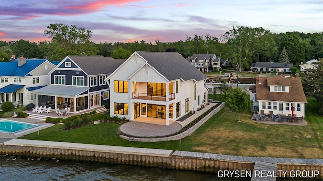 1351 Bayview Dr, Holland, MI 49423 - back of house at dusk with a patio area, a balcony, a water view, outdoor dining area, and a lawn