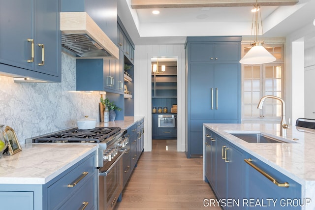 1351 Bayview Dr, Holland, MI 49423 - kitchen featuring stainless steel range, blue cabinetry, wall chimney exhaust hood, and wood finished floors