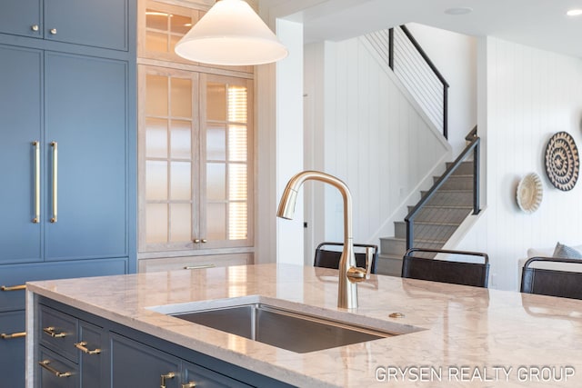 1351 Bayview Dr, Holland, MI 49423 - kitchen with light stone counters, a decorative wall, blue cabinets, healthy amount of natural light, and decorative light fixtures