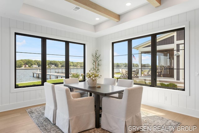 1351 Bayview Dr, Holland, MI 49423 - dining area featuring a decorative wall, beam ceiling, light wood-type flooring, and a water view