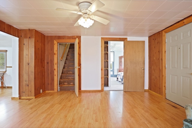 8075 Caine Rd, Millington, MI 48746 - unfurnished living room with wood walls, light wood-type flooring, stairs, and ceiling fan