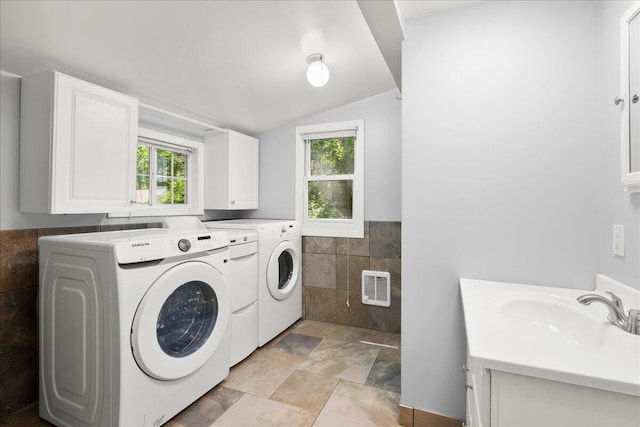 12915 S Englewright Dr, Sand Lake, MI 49343 - washroom featuring washing machine and dryer, tile walls, cabinet space, heating unit, and wainscoting