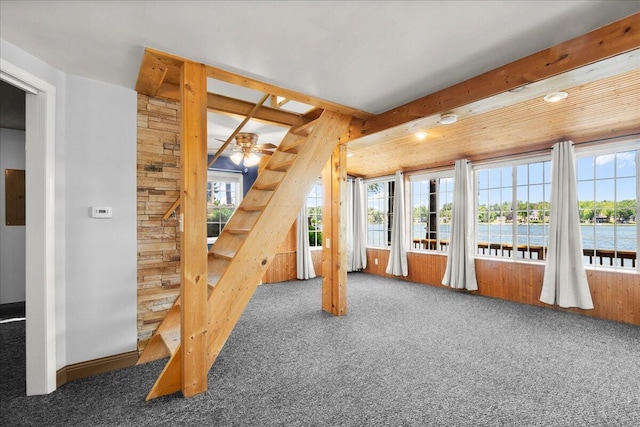 12915 S Englewright Dr, Sand Lake, MI 49343 - unfurnished living room with carpet, plenty of natural light, a ceiling fan, a water view, and wood walls