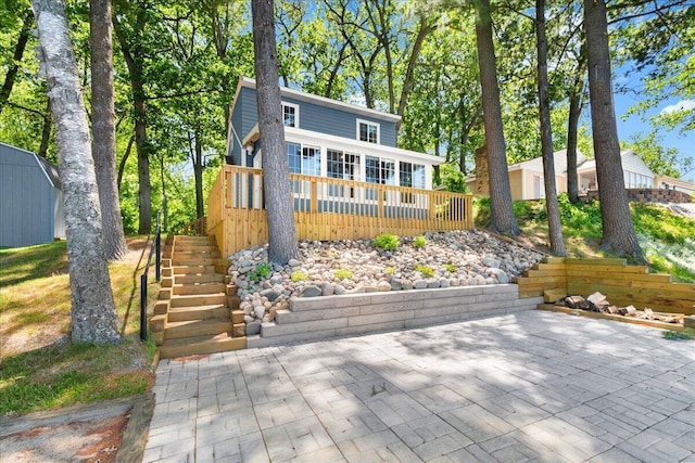 12915 S Englewright Dr, Sand Lake, MI 49343 - view of front of home featuring stairway, a deck, a storage unit, and a patio area