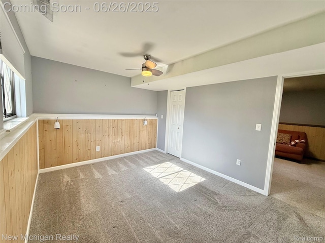 8588 Tim Tam Trl, Flushing, MI 48433 - unfurnished room featuring ceiling fan, wood walls, a wainscoted wall, and carpet flooring