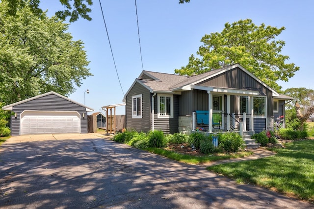 5255 E Holland Rd, Saginaw, MI 48601 - view of front of property featuring an outbuilding, a detached garage, board and batten siding, covered porch, and roof with shingles