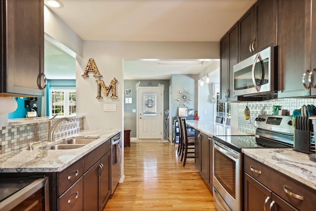5255 E Holland Rd, Saginaw, MI 48601 - kitchen with appliances with stainless steel finishes, dark brown cabinetry, backsplash, light wood finished floors, and beverage cooler