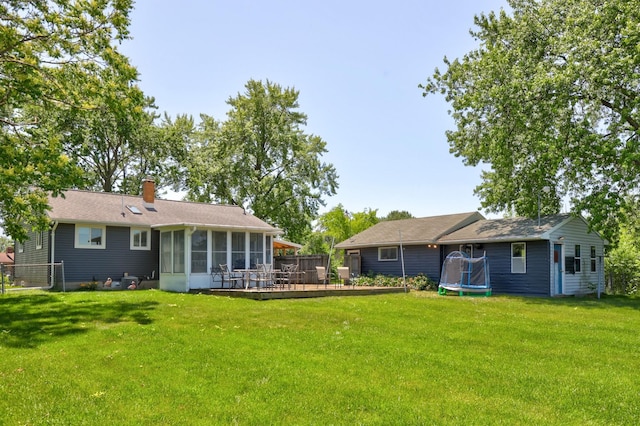 5255 E Holland Rd, Saginaw, MI 48601 - rear view of house with a trampoline, a sunroom, a chimney, and a wooden deck