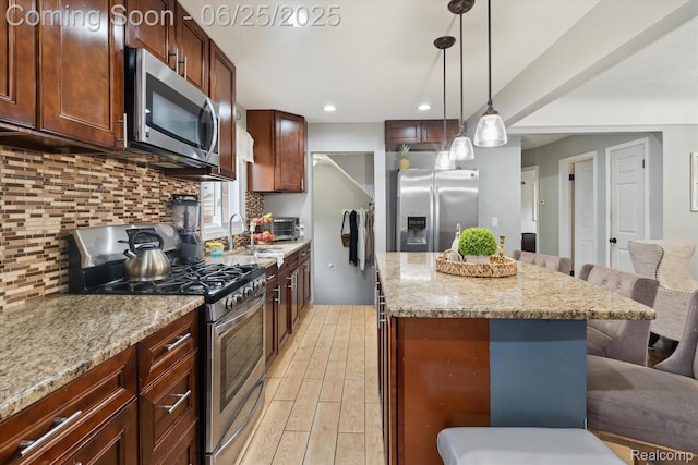 647 Farnham Ave, Lincoln Park, MI 48146 - kitchen with appliances with stainless steel finishes, a breakfast bar area, light wood-type flooring, backsplash, and a center island