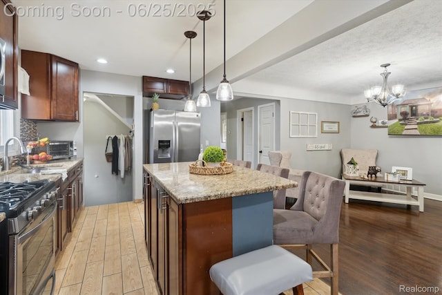 647 Farnham Ave, Lincoln Park, MI 48146 - kitchen featuring appliances with stainless steel finishes, light wood-style flooring, light stone counters, a center island, and hanging light fixtures