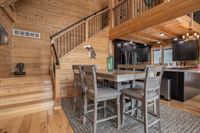 12349 N Sherman Lake Dr, Augusta, MI 49012 - dining space featuring wooden walls, light wood-style flooring, stairway, and a chandelier
