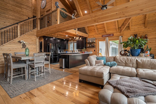 12349 N Sherman Lake Dr, Augusta, MI 49012 - living area with wood walls, a wood ceiling with exposed beams, high vaulted ceiling, light wood-style flooring, and stairs