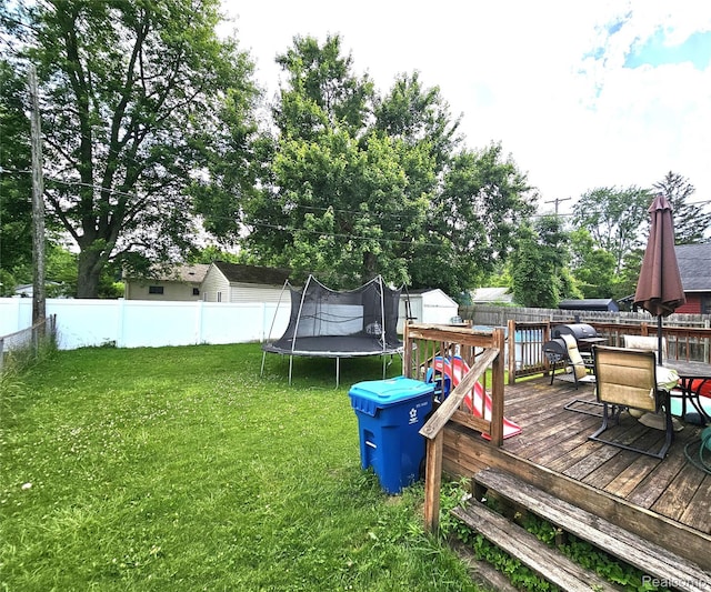 356 Spruce St, Mount Morris, MI 48458 - fenced backyard with a trampoline, a wooden deck, outdoor dining space, and a storage unit