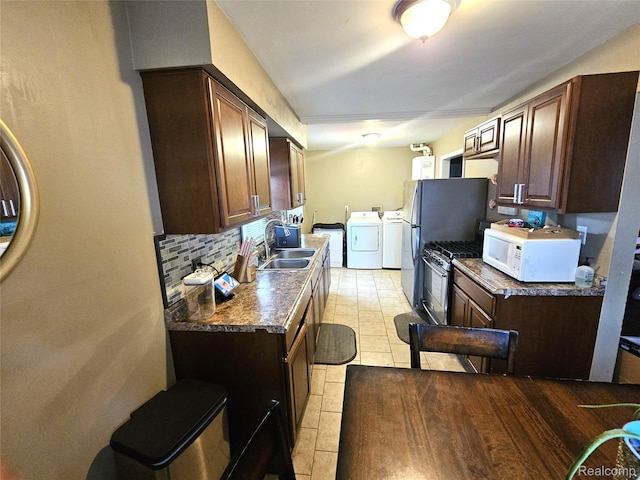 356 Spruce St, Mount Morris, MI 48458 - kitchen featuring washer and dryer, white microwave, dark countertops, and stainless steel gas range oven