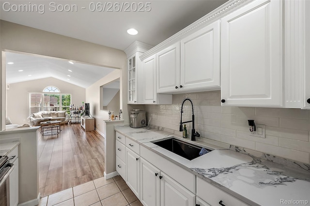 21958 Hartford Way, Macomb, MI 48042 - kitchen featuring lofted ceiling, white cabinetry, glass insert cabinets, backsplash, and open floor plan