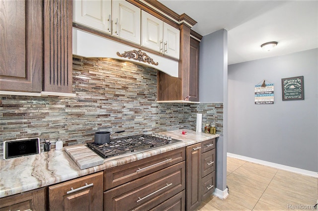 7471 Brewer Rd, Flint, MI 48507 - kitchen with stainless steel gas cooktop, light tile patterned flooring, decorative backsplash, and light stone counters