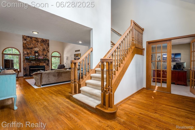 8123 Baypointe Dr, Brighton, MI 48114 - stairway featuring wood finished floors, a high ceiling, a stone fireplace, and french doors