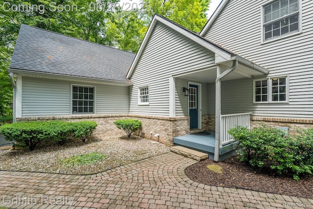 8123 Baypointe Dr, Brighton, MI 48114 - view of exterior entry featuring brick siding and a shingled roof