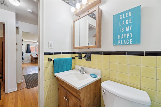 13210 Tecumseh Ave, Redford, MI 48239 - bathroom with vanity, tile walls, wood finished floors, a wainscoted wall, and ceiling fan