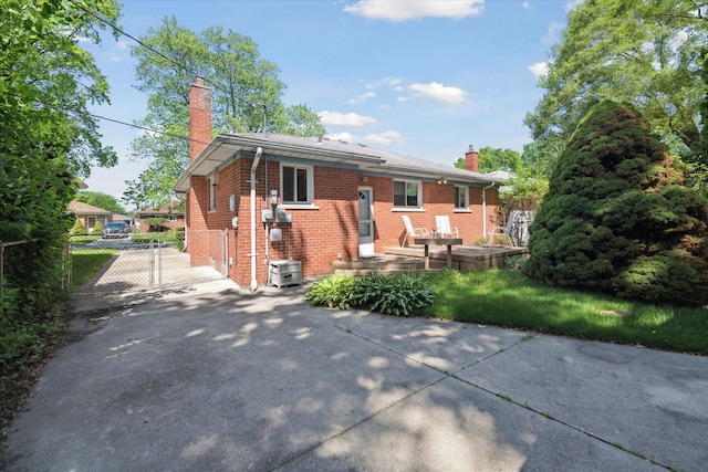 13210 Tecumseh Ave, Redford, MI 48239 - back of property featuring a chimney, brick siding, a gate, and concrete driveway