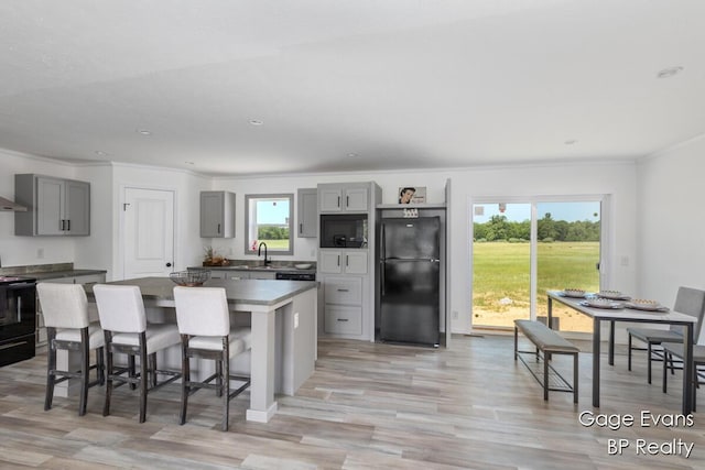19150 Yankee Rd, Morley, MI 49336 - kitchen featuring black appliances, gray cabinets, ornamental molding, light wood-type flooring, and a center island