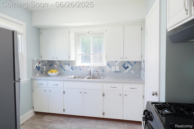 607 Chalmers St, Flint, MI 48503 - kitchen featuring freestanding refrigerator, decorative backsplash, light countertops, white cabinets, and range with gas cooktop