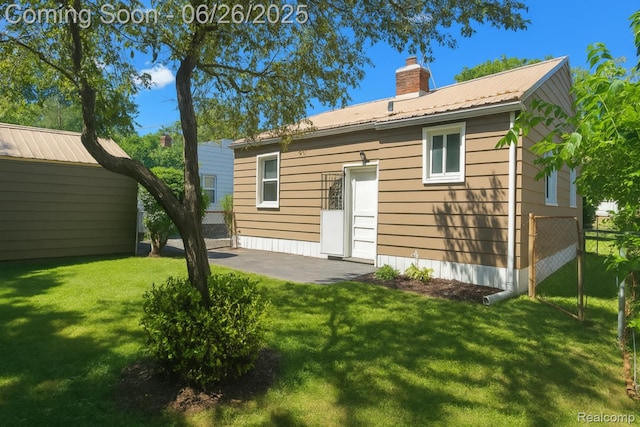 607 Chalmers St, Flint, MI 48503 - rear view of property with a chimney, a metal roof, and a patio area
