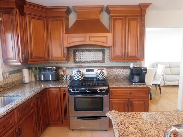 41431 Tarragon Dr, Sterling Heights, MI 48314 - kitchen featuring stainless steel range with gas cooktop, premium range hood, light stone counters, and tasteful backsplash