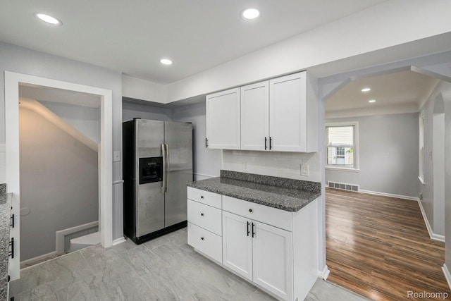 2856 Academy St, Dearborn, MI 48124 - kitchen with stainless steel refrigerator with ice dispenser, white cabinetry, arched walkways, dark stone countertops, and recessed lighting