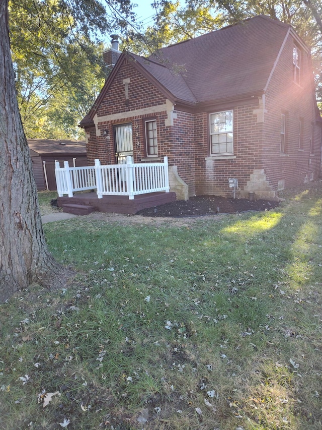 6303 Guilford St, Detroit, MI 48224 - view of front of property featuring brick siding, a wooden deck, a front yard, and a chimney