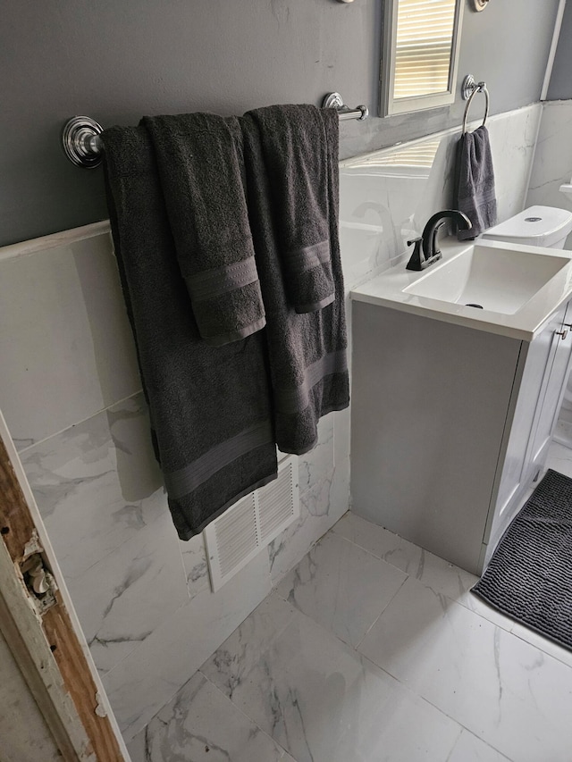 6303 Guilford St, Detroit, MI 48224 - bathroom with vanity, marble look tile flooring, and wainscoting