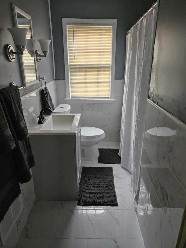 6303 Guilford St, Detroit, MI 48224 - bathroom with marble finish flooring, vanity, tile walls, a wainscoted wall, and healthy amount of natural light
