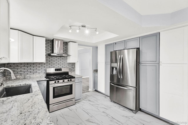 14717 Dane Ct, Sterling Heights, MI 48312 - kitchen with appliances with stainless steel finishes, wall chimney exhaust hood, a raised ceiling, light marble finish flooring, and light stone counters