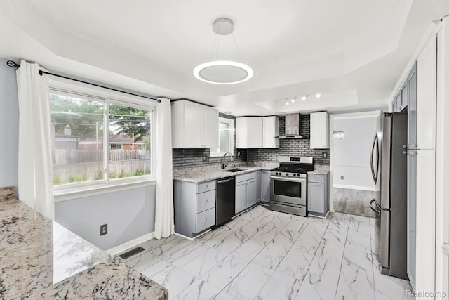 14717 Dane Ct, Sterling Heights, MI 48312 - kitchen with a tray ceiling, stainless steel appliances, wall chimney range hood, light stone countertops, and light marble finish floors