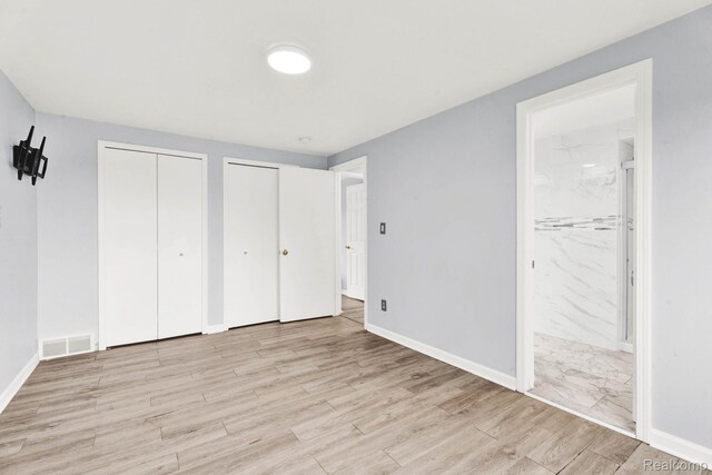 14717 Dane Ct, Sterling Heights, MI 48312 - unfurnished bedroom featuring multiple closets, wood finished floors, and ensuite bath