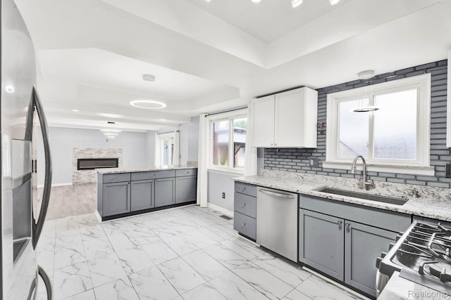 14717 Dane Ct, Sterling Heights, MI 48312 - kitchen with appliances with stainless steel finishes, a tray ceiling, light stone counters, and light marble finish flooring