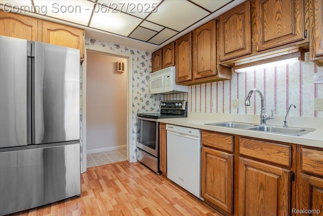14711 Paris St, Allen Park, MI 48101 - kitchen with stainless steel appliances, light countertops, wallpapered walls, brown cabinets, and light wood-style flooring