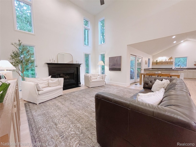 5403 Lenard Cir, Howell, MI 48843 - living area featuring high vaulted ceiling, plenty of natural light, a fireplace with flush hearth, recessed lighting, and light wood-style flooring