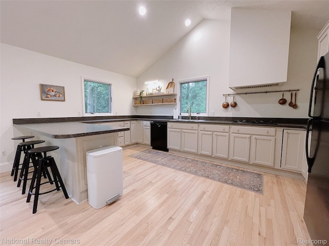 5403 Lenard Cir, Howell, MI 48843 - kitchen with black appliances, a peninsula, a breakfast bar area, light wood-style floors, and open shelves