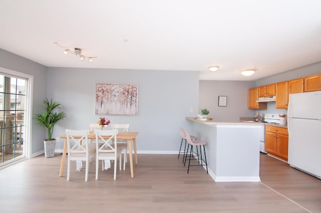 2769 Barclay Way, Ann Arbor, MI 48105 - kitchen with white appliances, under cabinet range hood, light wood finished floors, a breakfast bar, and light countertops