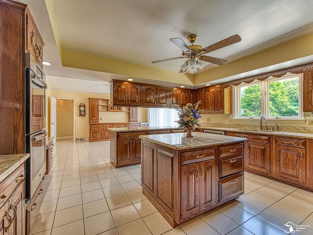 255 Maywood Ave, Monroe, MI 48162 - kitchen with a center island, light tile patterned floors, ceiling fan, double oven, and light stone countertops